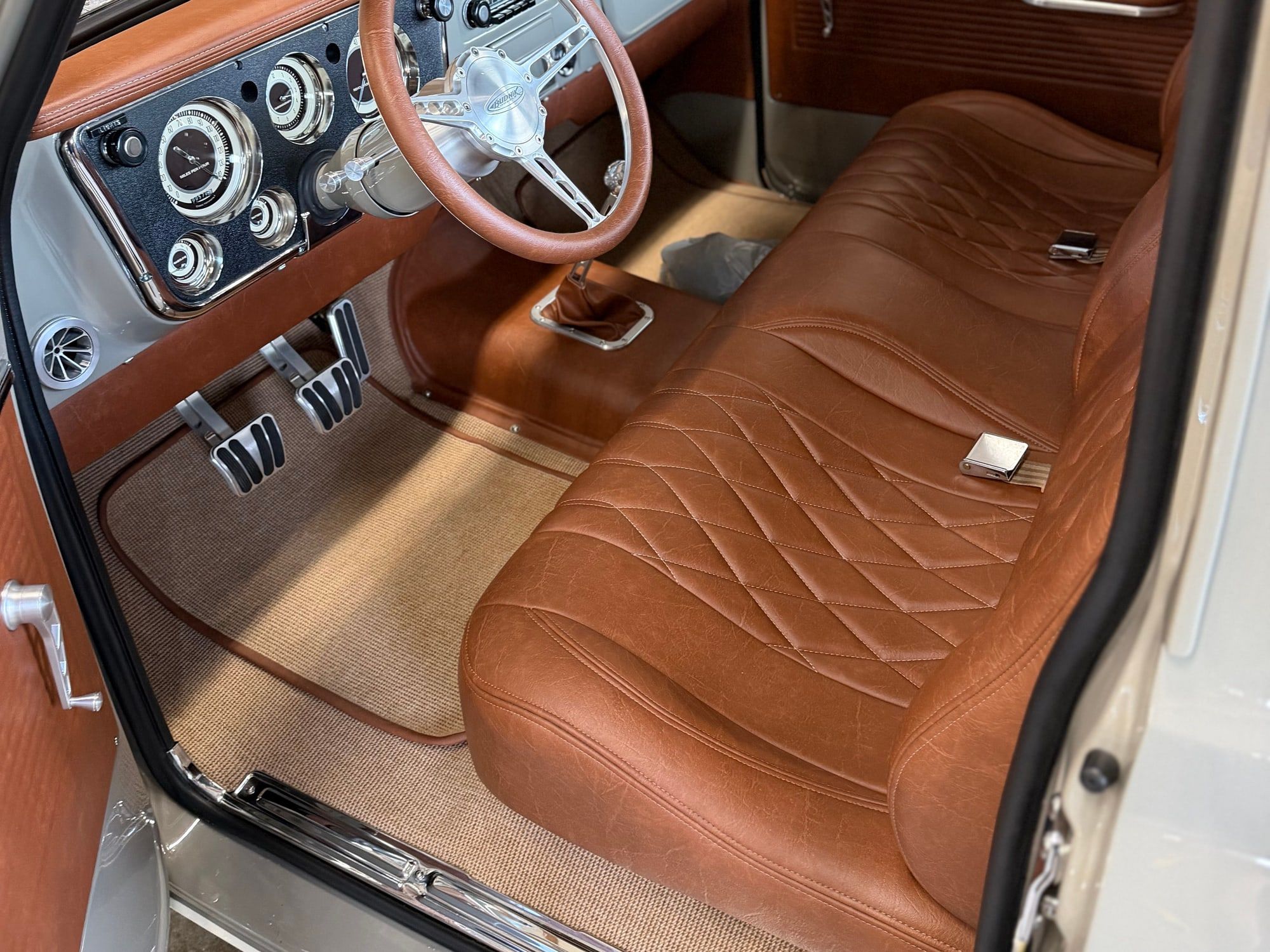 Restored classic truck cabin with clean tan leather bench seat and chrome dash